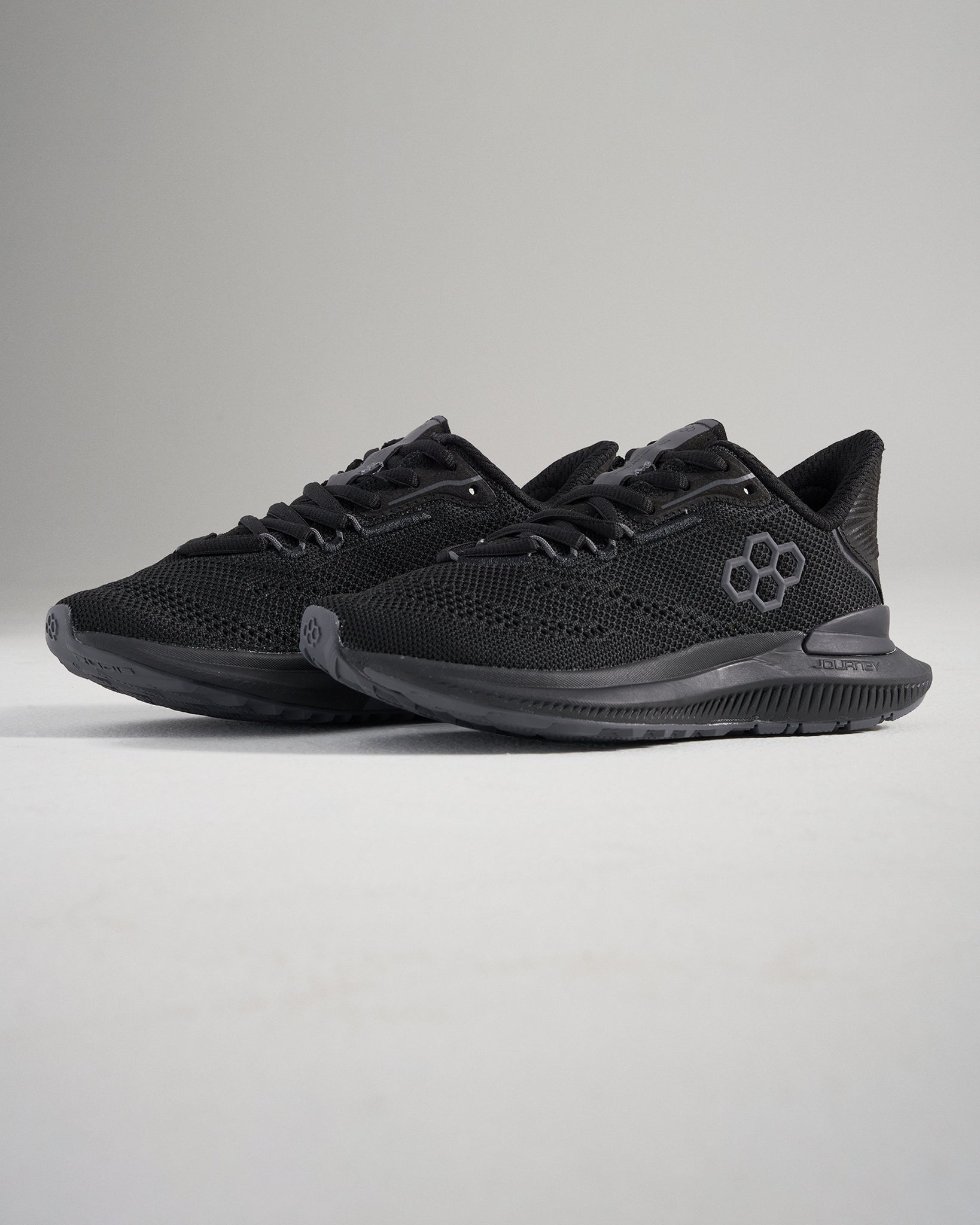 A pair of sleek black athletic shoes featuring a breathable mesh upper and a textured sole for grip and performance