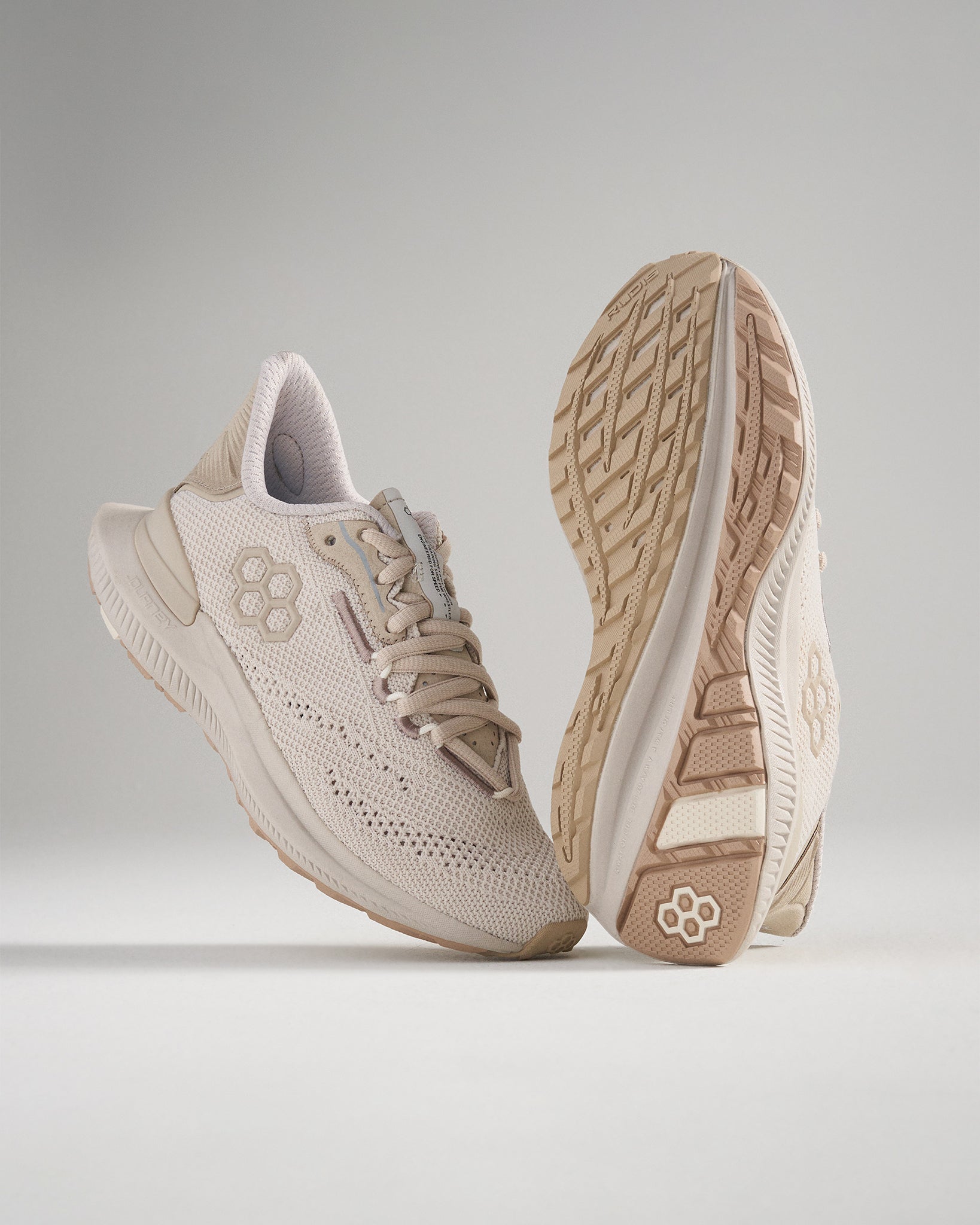 A pair of beige athletic shoes featuring a breathable mesh upper and a textured sole designed for performance and comfort