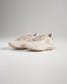 A pair of light beige athletic shoes designed for comfort and performance featuring a textured mesh upper and a supportive sole