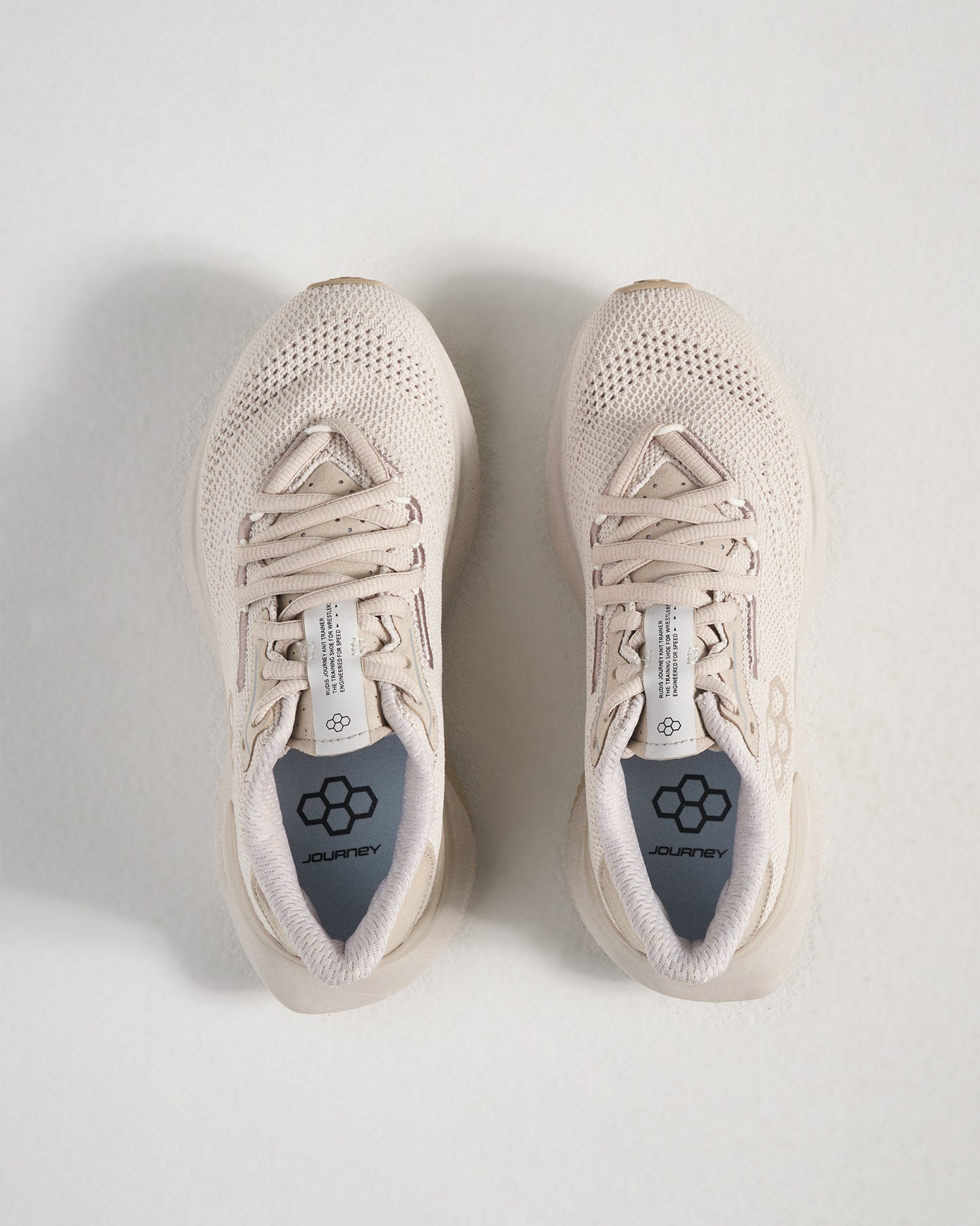 A top view of a pair of light beige running shoes featuring a breathable mesh upper and a cushioned insole labeled JOURNEY