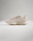 A side view of a light beige athletic shoe featuring a breathable mesh upper designed for comfort and performance