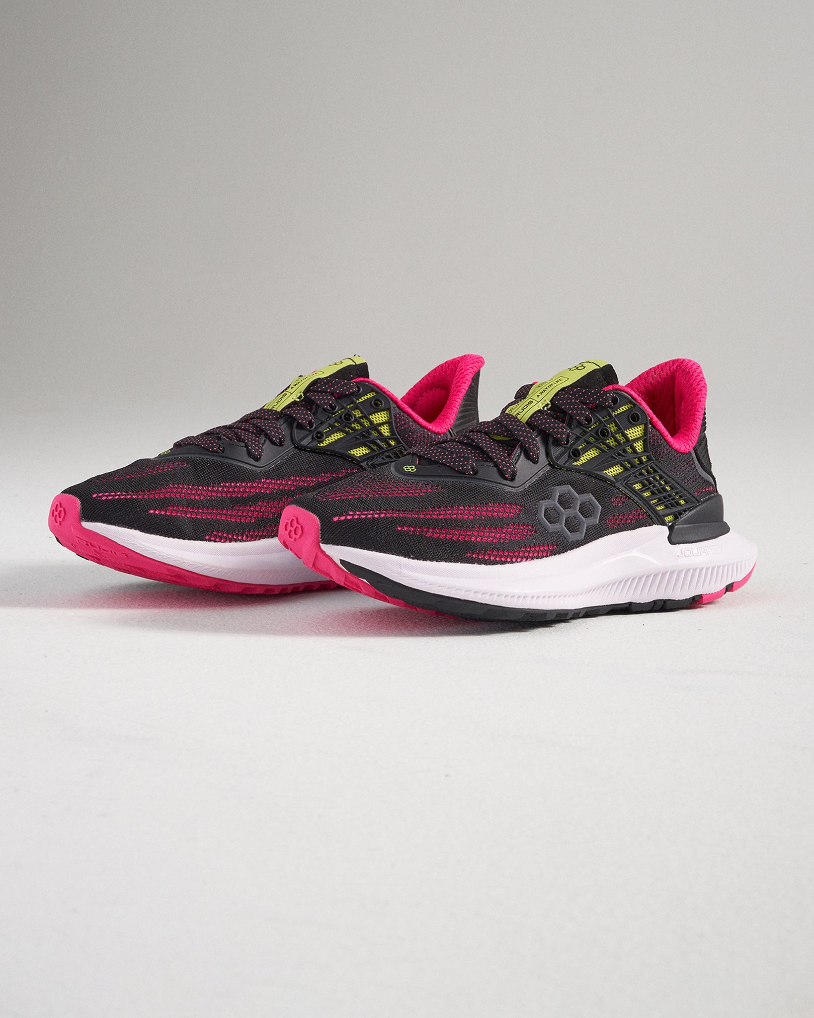 This image displays a pair of modern black athletic shoes accented with bright pink and lime green details showcasing a sleek design suitable for both performance and casual wear