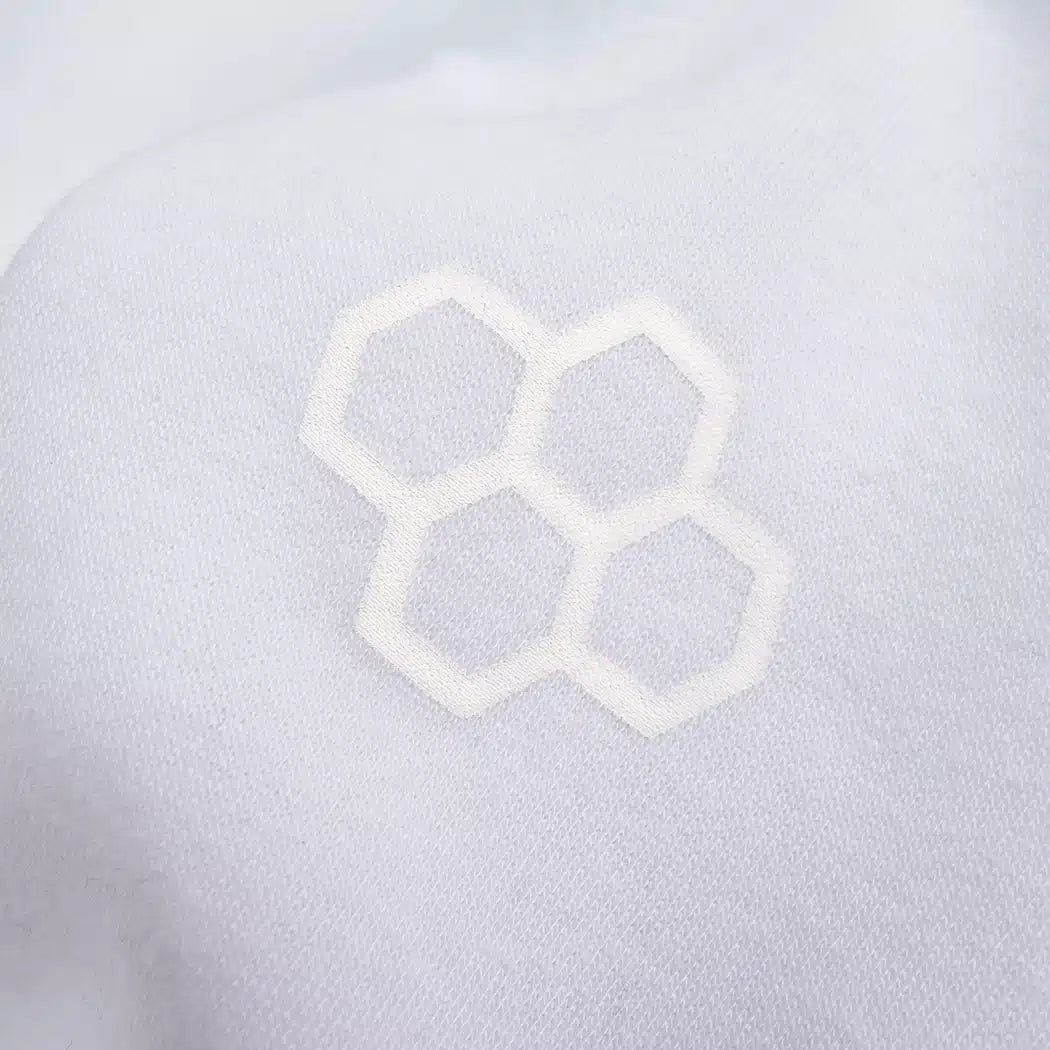 A close-up of a textured fabric featuring a subtle white honeycomb pattern embroidered on a light background