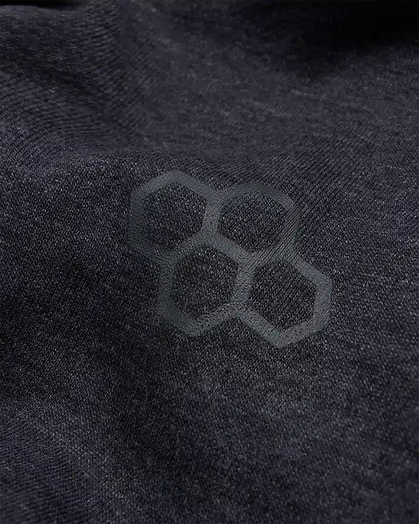 A close-up view of black fabric featuring a subtle hexagonal pattern highlighting texture and design details