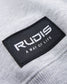 A close-up of a gray fabric showcasing a black label with the word RUDIS and the phrase A WAY OF LIFE