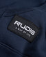 A close-up view of a black label on a navy fabric featuring the brand name RUDIS and the tagline A WAY OF LIFE