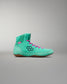 High-top athletic shoe in a vibrant teal color with bright pink laces and a black hexagonal logo, designed for performance and showcasing a textured synthetic upper against a gradient gray background.