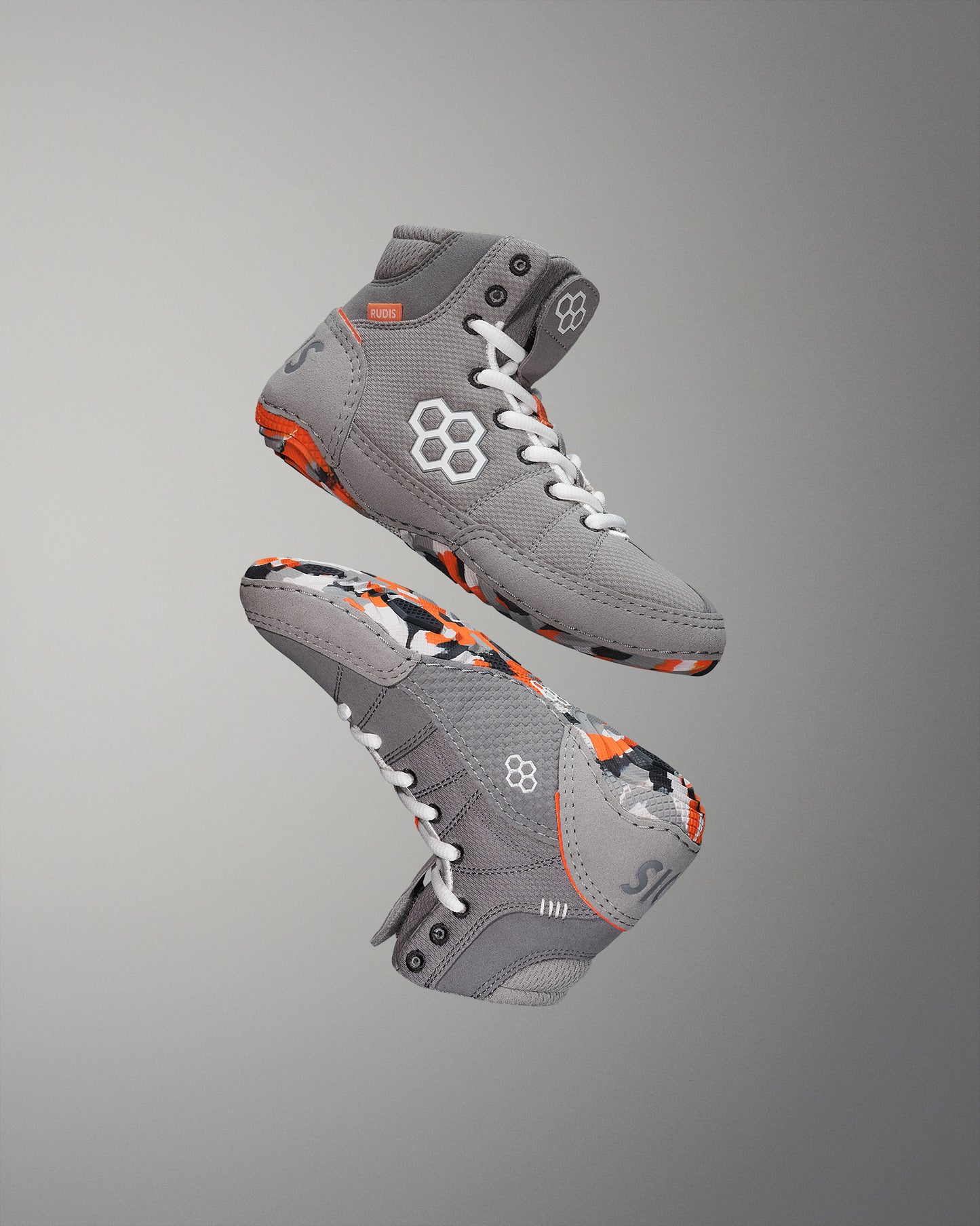 High-top wrestling shoes in gray highlight their textured upper and patterned sole with white laces and an orange accent label 'RUDIS'.