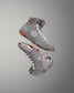 High-top wrestling shoes in gray highlight their textured upper and patterned sole with white laces and an orange accent label 'RUDIS'.