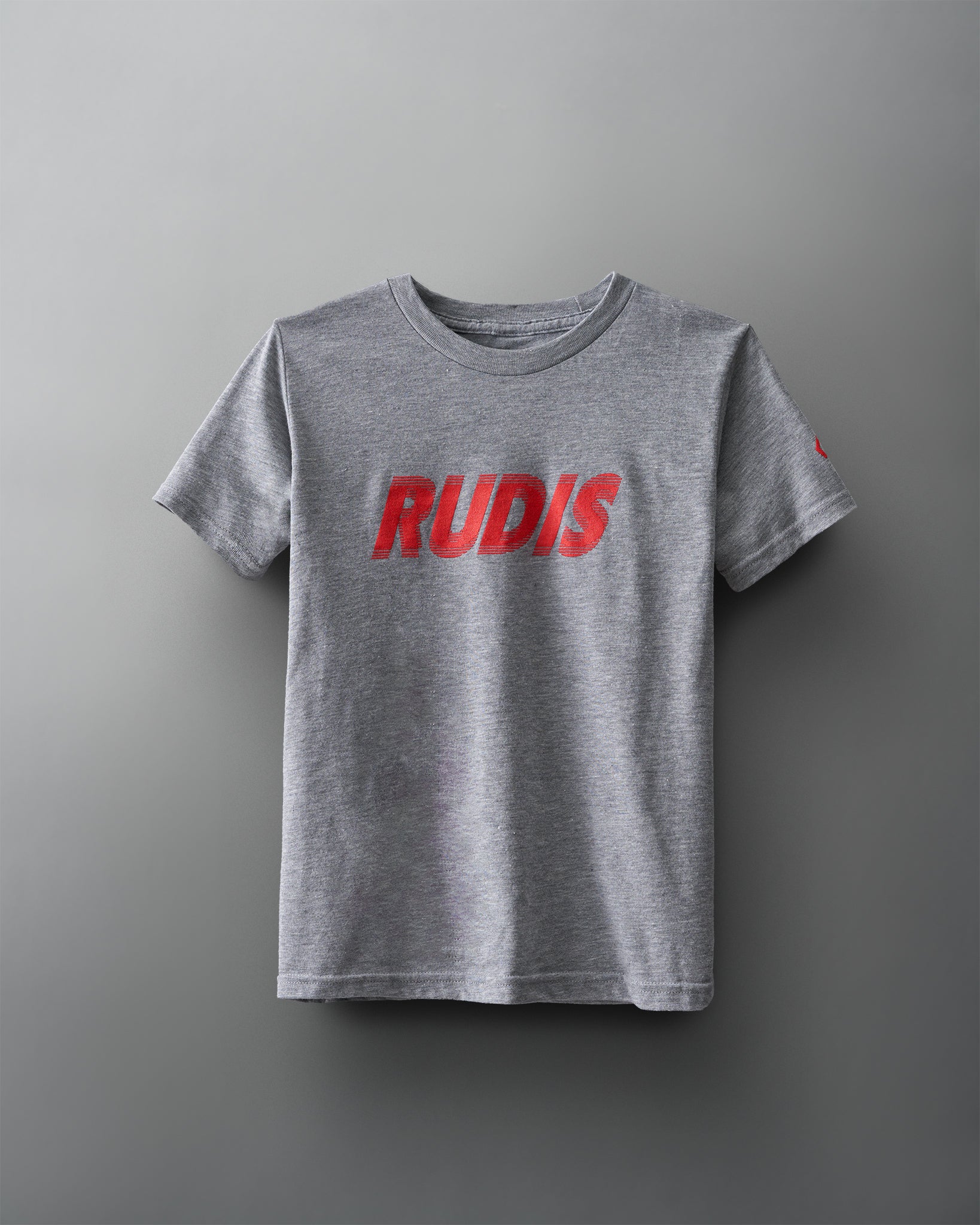 A gray t-shirt with a soft texture features 'RUDIS' in bold red lettering on the front, emphasizing its athletic and casual appeal.