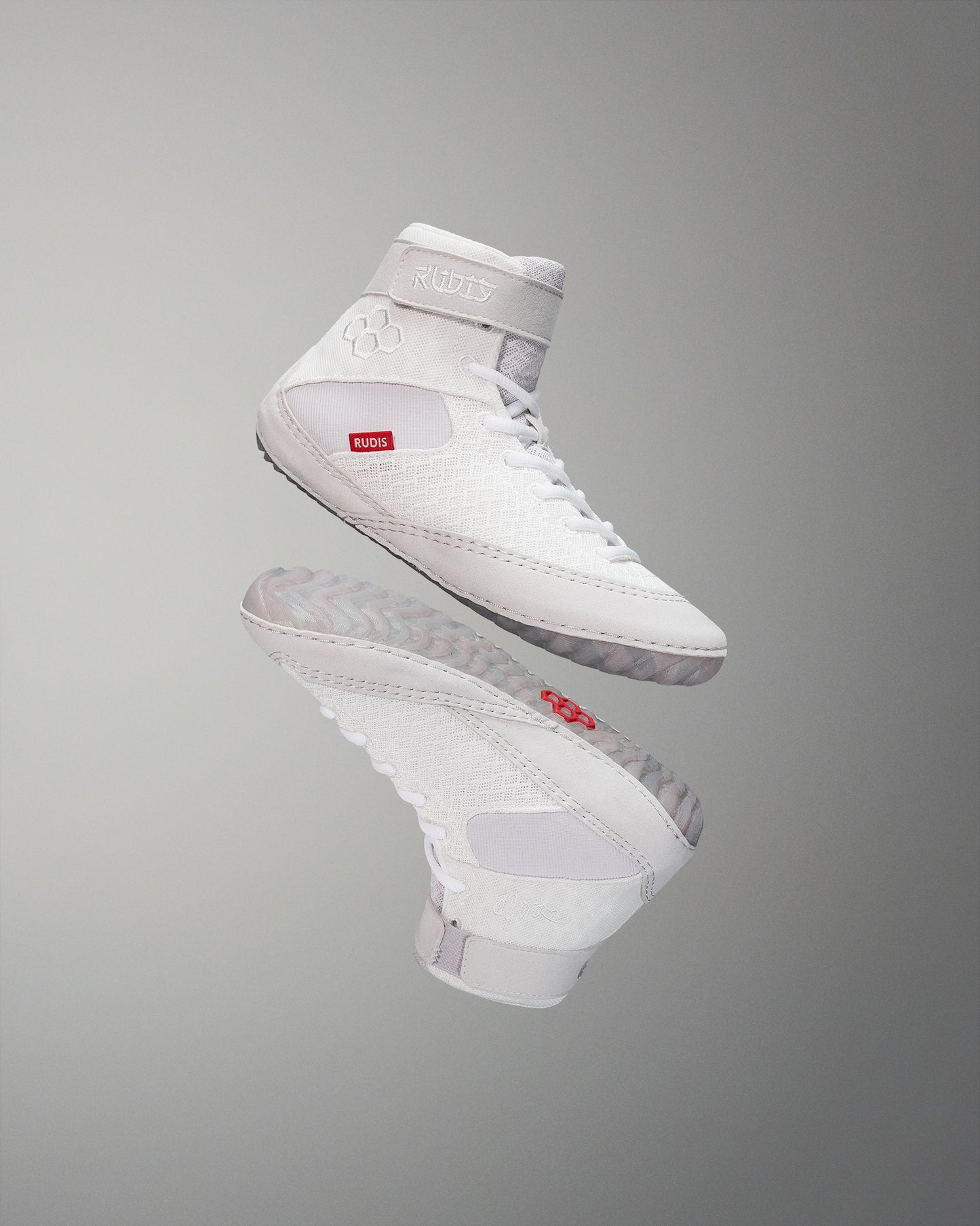 High-performance white wrestling shoes, designed with textures and a padded collar for support, showcase a red logo against a soft gradient background.