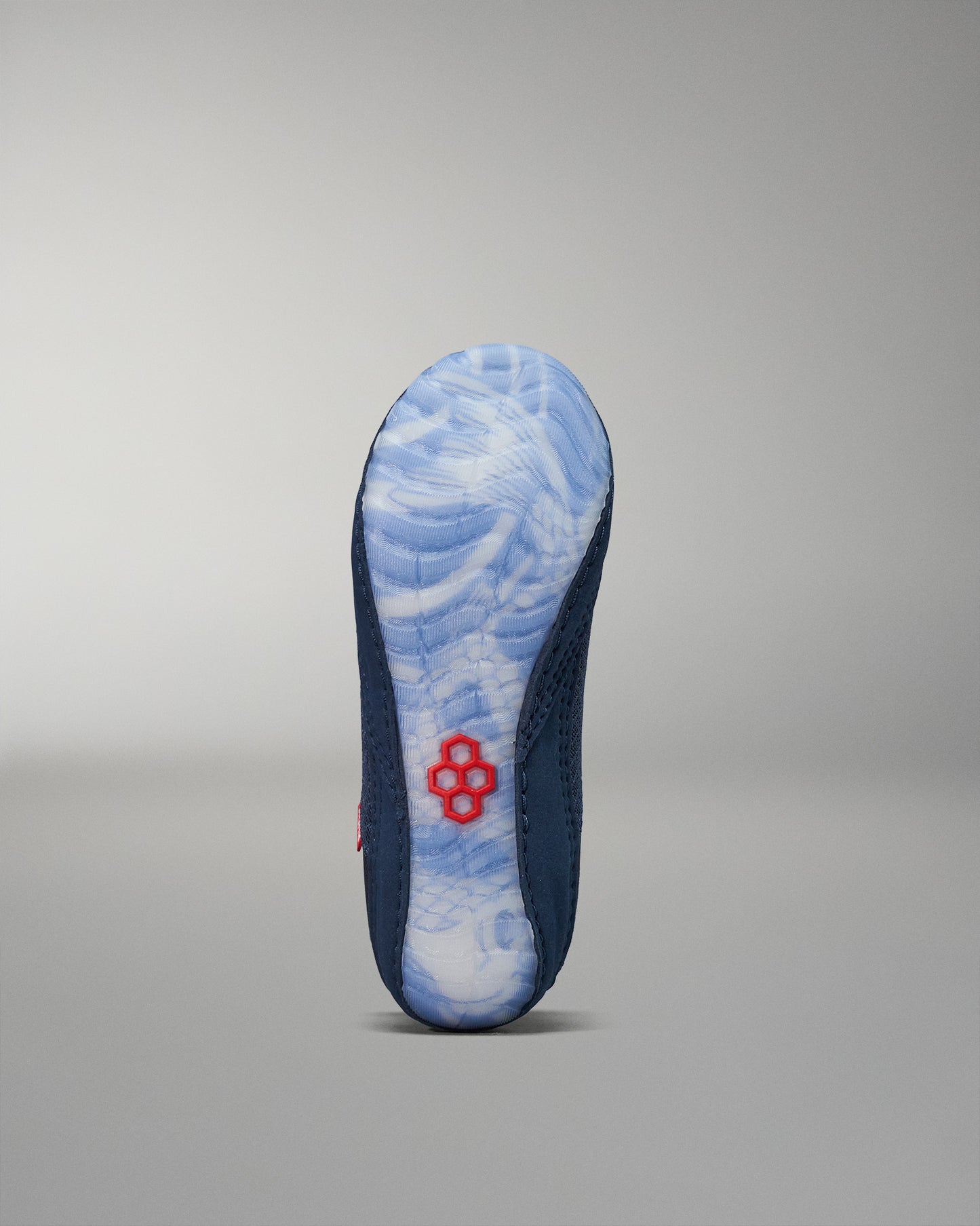 The shoe's sole showcases a blue and white marbled design, complemented by a navy upper and a striking red accent, all set against a soft gray background.