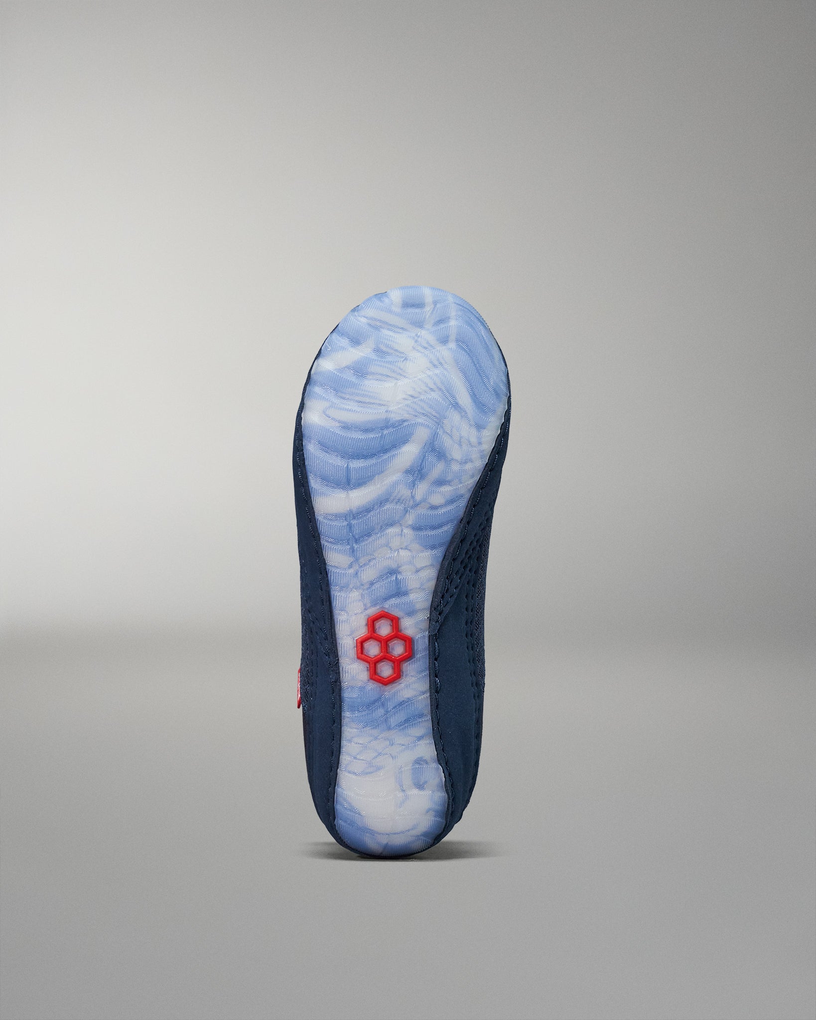 The shoe's sole showcases a blue and white marbled design, complemented by a navy upper and a striking red accent, all set against a soft gray background.