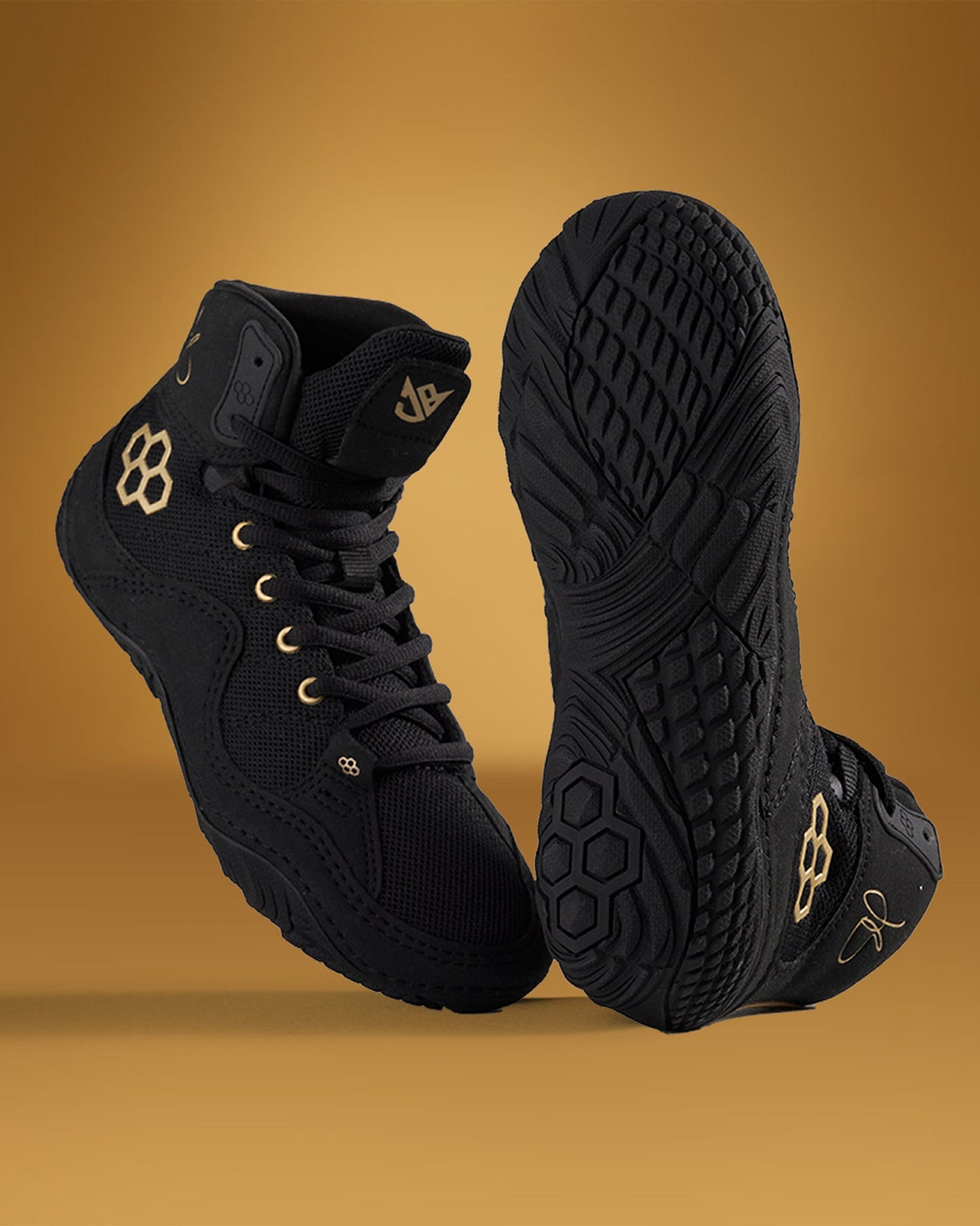 A stylish pair of black high-top sneakers with gold accents positioned on a warm golden background to highlight their sleek design