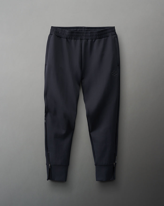 Black athletic pants with an elastic waistband and zippered cuffs, designed for comfort and functionality, are featured against a muted gray background.