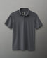 A dark gray polo shirt with a classic collar and a branding detail on the chest, suitable for various occasions.