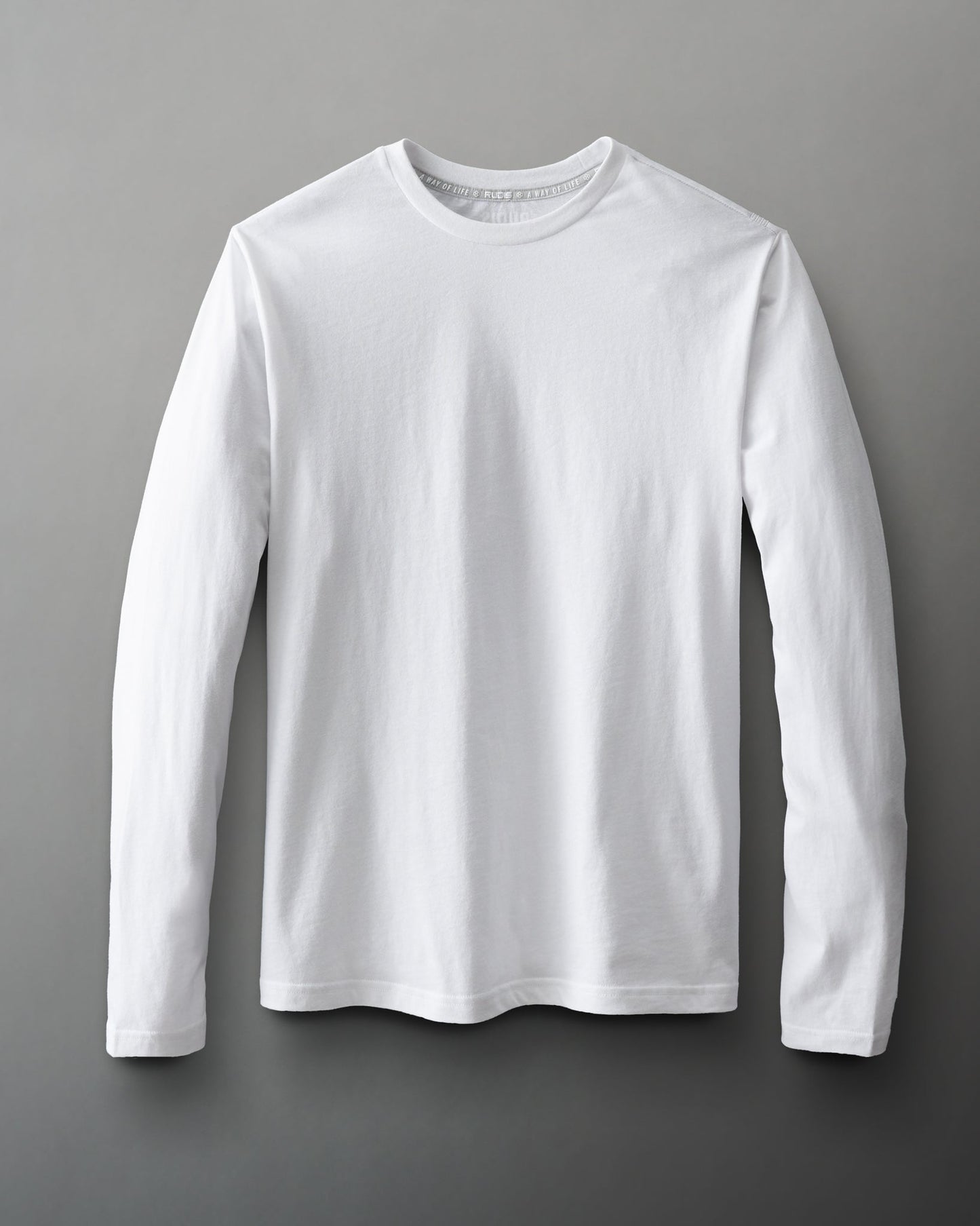 A long-sleeved white t-shirt on a muted gray background showcases a plain design with a crew neckline and full sleeves, emphasizing versatility for casual wear.