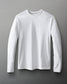 A long-sleeved white shirt with a round neckline is laid flat on a gray surface, showcasing a simple and versatile design.