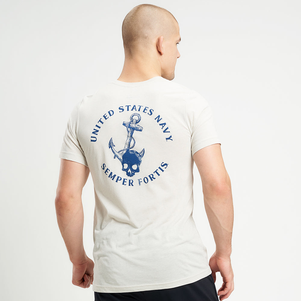 A male model showcases a light-colored t-shirt featuring a United States Navy design with a skull and anchor on the back paired with black athletic shorts