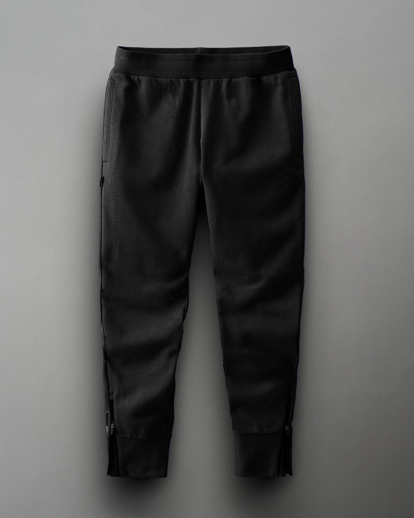 Black athletic pants with a minimalist design feature an elastic waistband and ankle zippers, combining style and functionality.