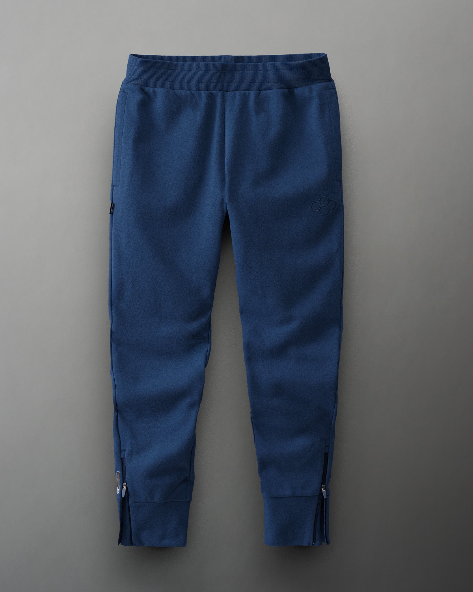 Navy blue athletic pants with a functional design, featuring zippered cuffs, side pockets, and an elastic waistband for comfort.